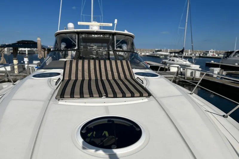 Slide: The Image of 2005 Regal Commodore 4260 yacht with striped sunbed, docked in marina under clear blue sky. - 34