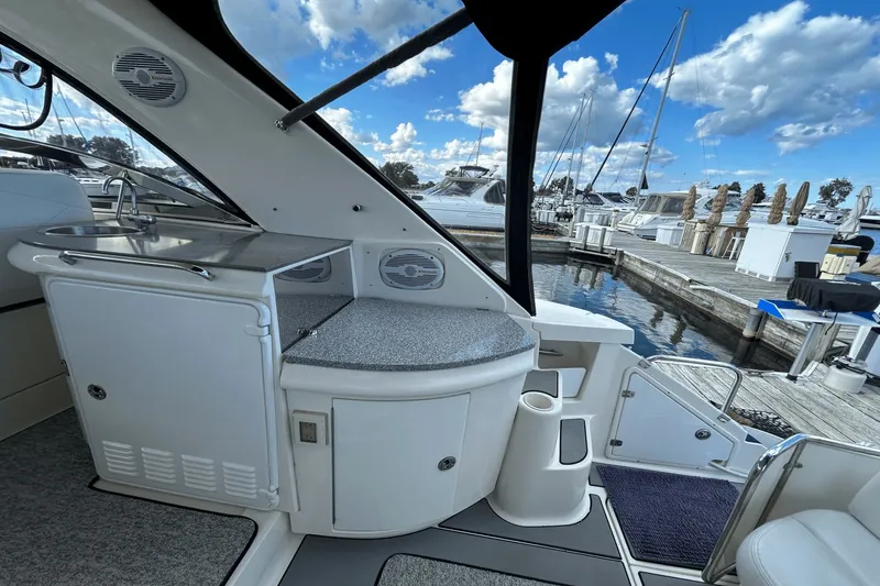 Slide: The Image of 2005 Regal Commodore 4260 yacht interior with kitchenette, docked at marina under blue sky. - 5