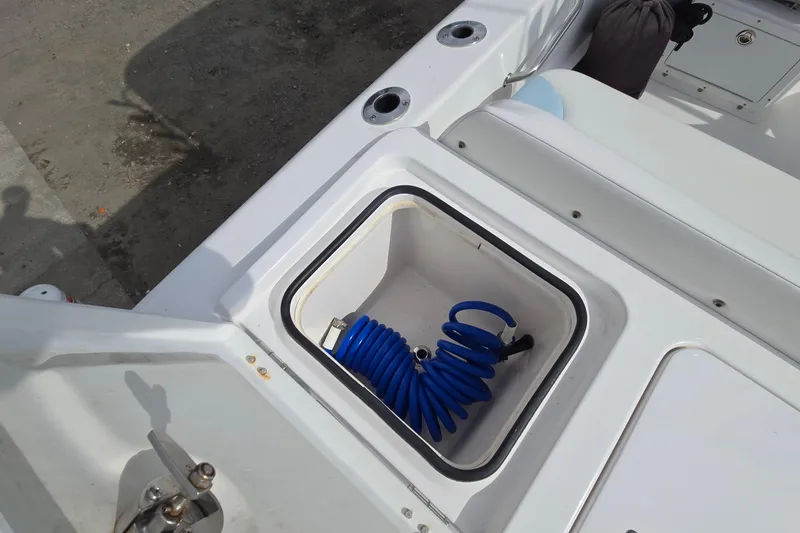 Slide: The Image of 2020 Twin Vee 240 DC GF boat deck with storage compartment and coiled hose. - 27