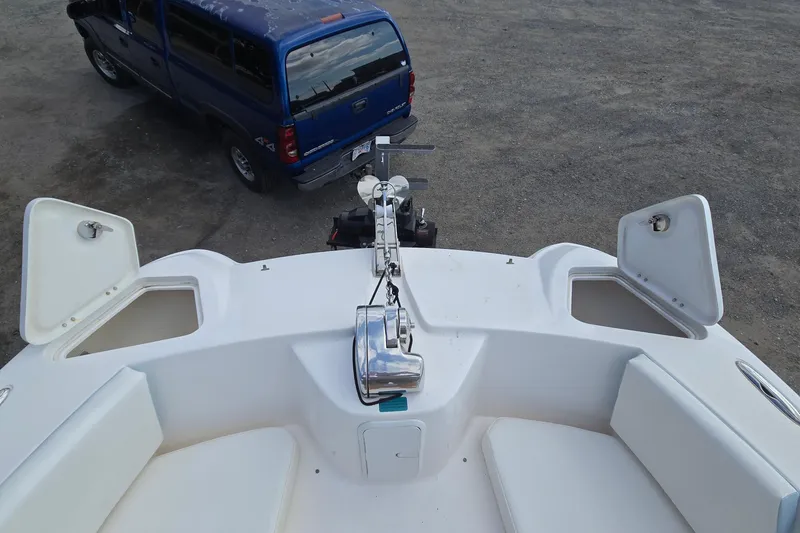 Slide: The Image of 2020 Twin Vee 240 DC GF boat bow with open storage compartments, parked near a blue truck. - 62