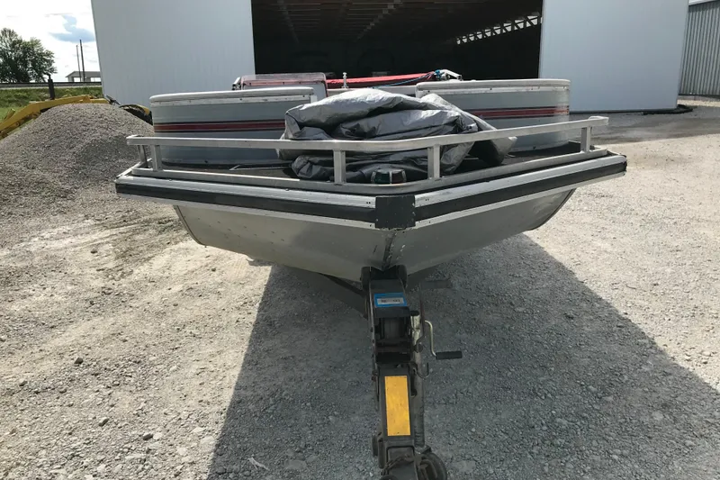Slide: The Image of 1991 Lowe 2200 boat on trailer, parked on gravel near a storage building. - 3