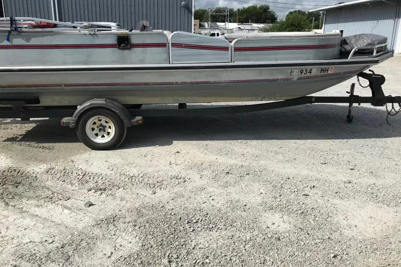 Slide: The Image of 1991 Lowe 2200 boat on trailer, parked on gravel near industrial building. - 4