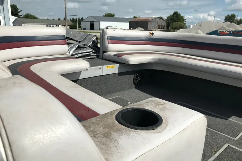 Slide: The Image of 1991 Lowe 2200 boat interior with white and red seating, cup holder, and outdoor setting. - 6
