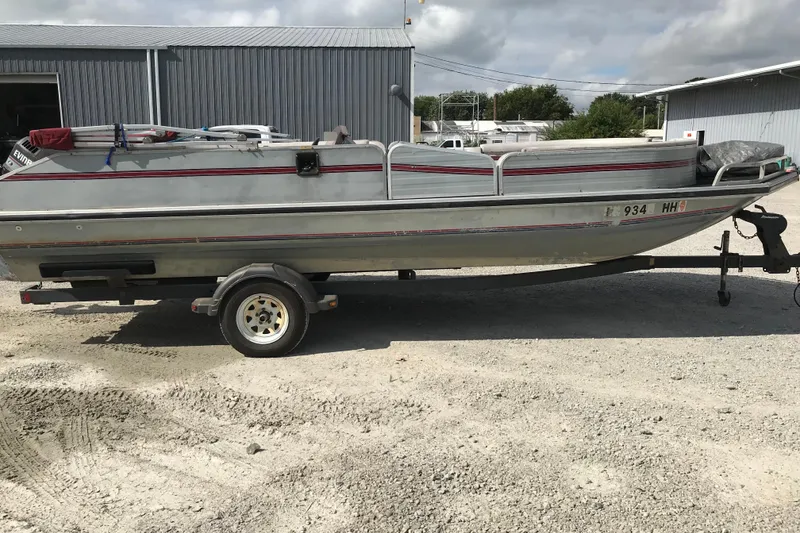 Slide: The Image of 1991 Lowe 2200 boat on trailer, parked outdoors near metal buildings. - 8