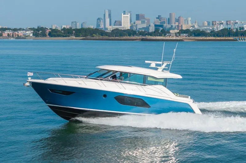 Slide: The Image of 2022 Tiara Yachts Coupe cruising on water with city skyline in background. - 32