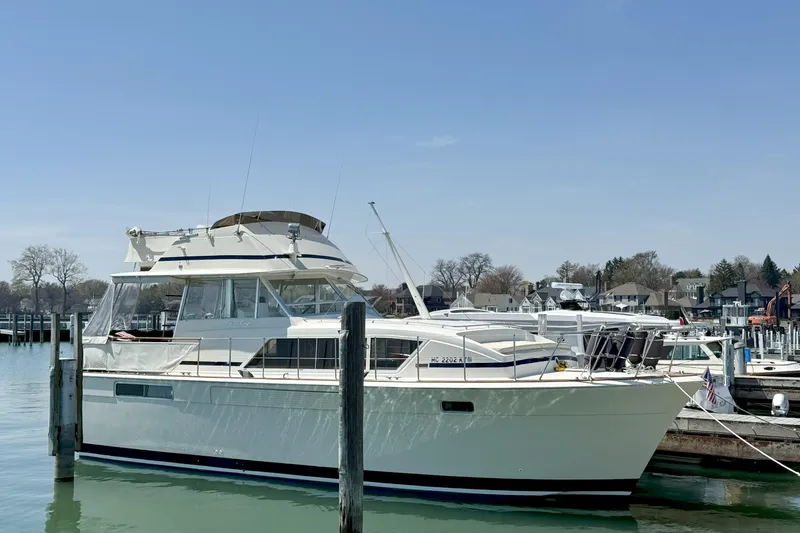 The Image of 1978 Chris-Craft 410 Commander yacht docked at marina under blue sky. - 0