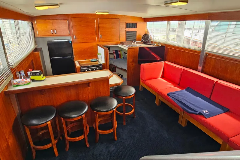 Slide: The Image of Interior of 1978 Chris-Craft 410 Commander with red seating, bar stools, and kitchen area. - 14