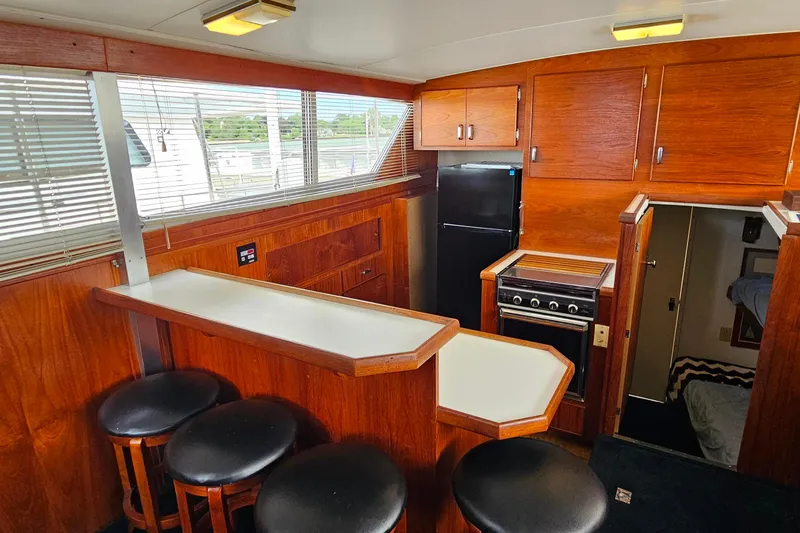 Slide: The Image of 1978 Chris-Craft 410 Commander interior with wood cabinetry, bar seating, and kitchen area. - 17