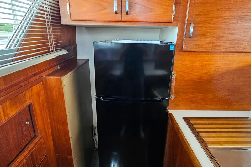 Slide: The Image of 1978 Chris-Craft 410 Commander kitchen with black refrigerator and wooden cabinetry. - 21