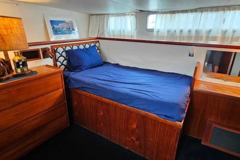 Slide: The Image of Cozy cabin interior of 1978 Chris-Craft 410 Commander with wooden furniture and blue bedding. - 24