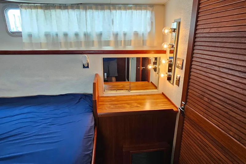 Slide: The Image of 1978 Chris-Craft 410 Commander cabin with wooden vanity, mirror, and blue bedding. - 25