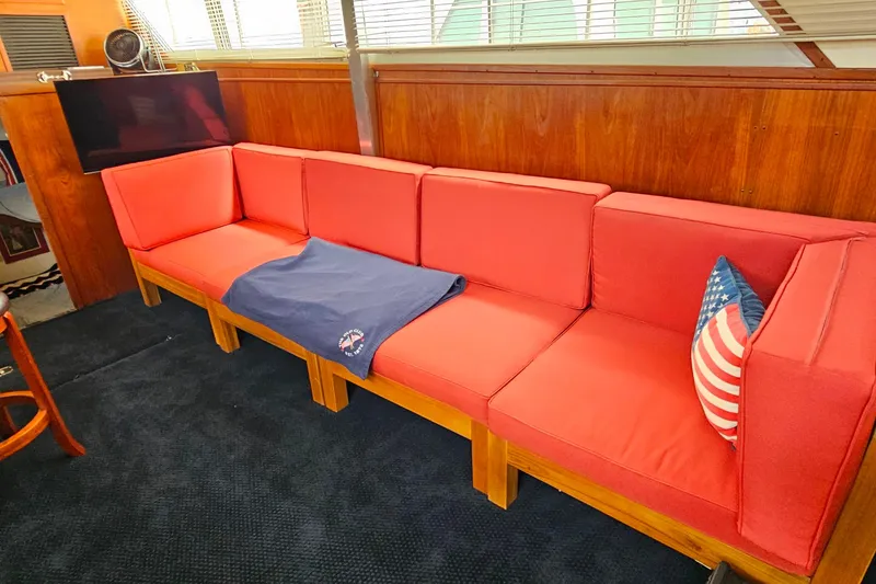 Slide: The Image of Red cushioned seating area inside a 1978 Chris-Craft 410 Commander yacht, with American flag pillow. - 28