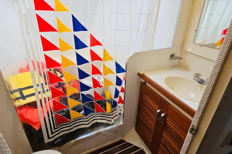 Slide: The Image of 1978 Chris-Craft 410 Commander bathroom with colorful shower curtain and wooden cabinet. - 31