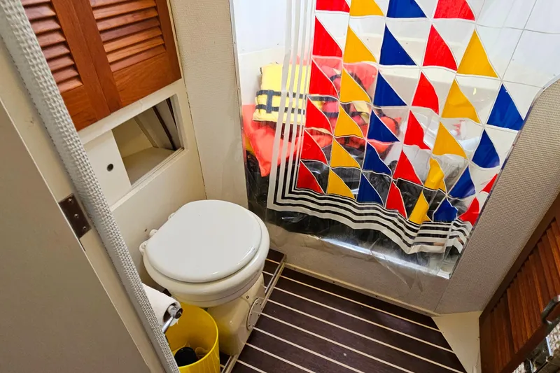Slide: The Image of 1978 Chris-Craft 410 Commander bathroom with colorful shower curtain and wooden accents. - 32