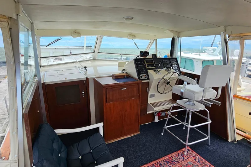 Slide: The Image of 1978 Chris-Craft 410 Commander helm with vintage controls and seating, overlooking marina. - 5