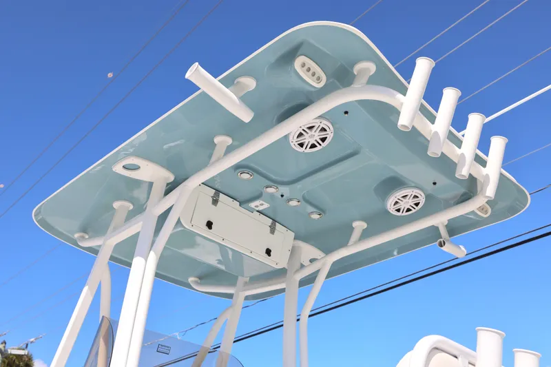 Slide: The Image of 2026 Sea Hunt Ultra 229 boat T-top with rod holders and speakers against blue sky. - 22