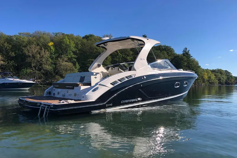Slide: The Image of 2017 Chaparral 337 SSX boat on calm water, surrounded by lush greenery. - 1