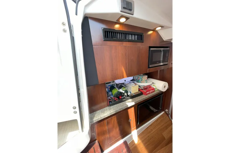 Slide: The Image of 2017 Chaparral 337 SSX interior with wooden cabinetry, microwave, and countertop items. - 22