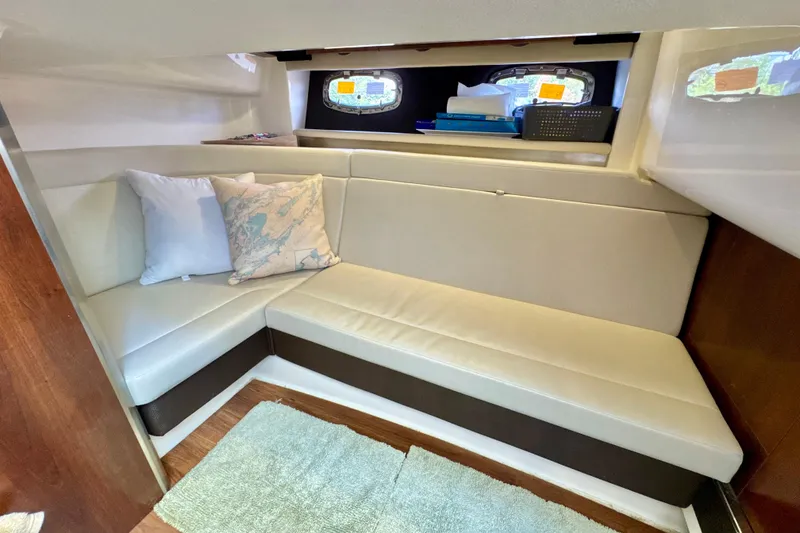 Slide: The Image of 2017 Chaparral 337 SSX cabin interior with cozy seating and nautical-themed pillows. - 23