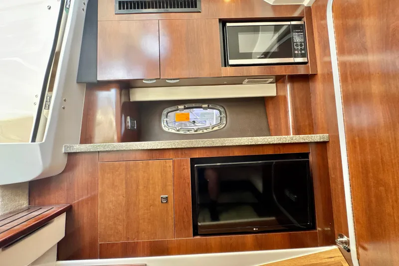 Slide: The Image of 2017 Chaparral 337 SSX interior with microwave, wooden cabinetry, and small window. - 26
