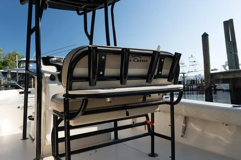Slide: The Image of 2021 Sea Chaser 26 LX boat interior with seating and rod holders at a marina. - 32