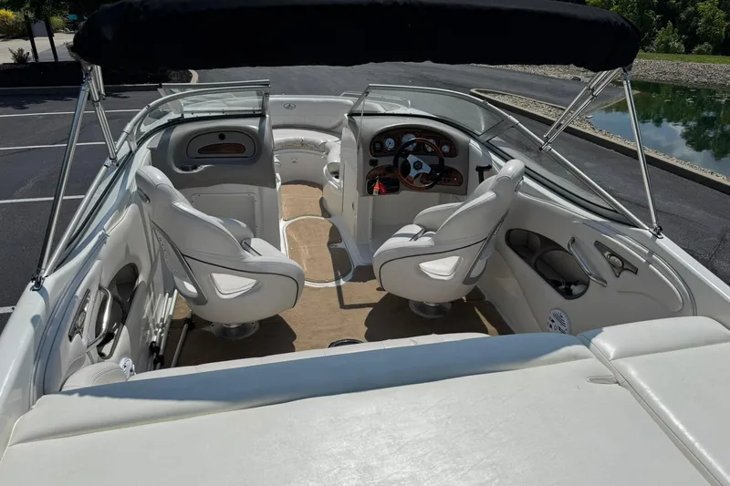 Slide: The Image of 2006 Ebbtide 2100 Bow Rider interior with seating and steering wheel, parked near water. - 13