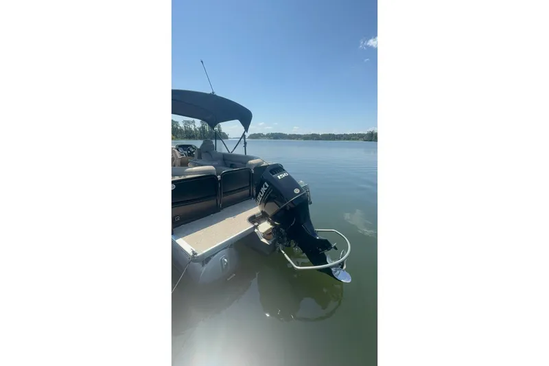 Slide: The Image of 2023 Premier Sunsation boat with outboard motor on a calm lake under clear skies. - 10