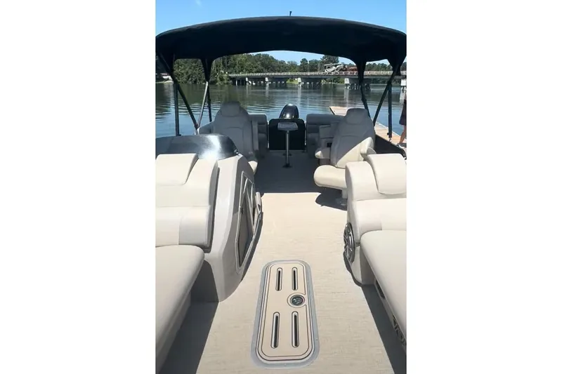 Slide: The Image of 2023 Premier Sunsation boat interior with beige seating and canopy on a calm lake. - 9