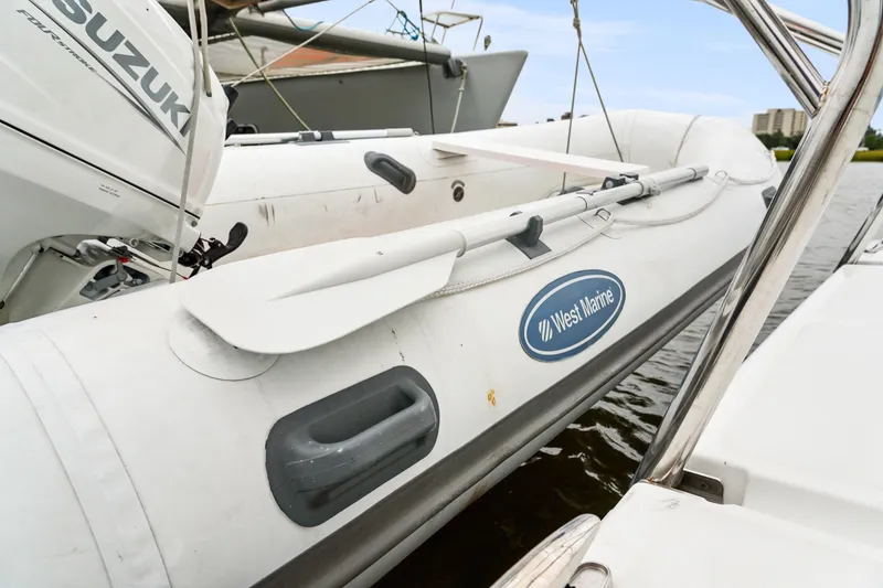 Slide: The Image of Inflatable boat with Suzuki motor, West Marine logo, docked on water. - 107