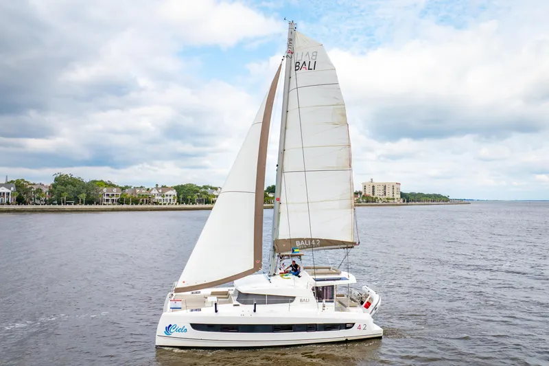 Slide: The Image of Sailing catamaran Bali 4.2, 2023 model, cruising on a calm river under cloudy skies. - 109