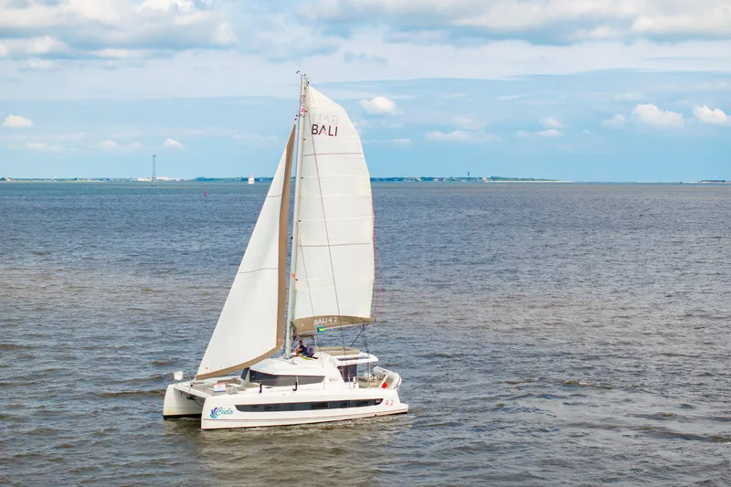 Slide: The Image of 2023 Bali 4.2 catamaran sailing on open sea under a partly cloudy sky. - 114