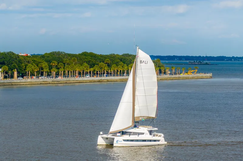 Slide: The Image of Sailing catamaran Bali 4.2, 2023 model, cruising near a scenic coastline with palm trees. - 118