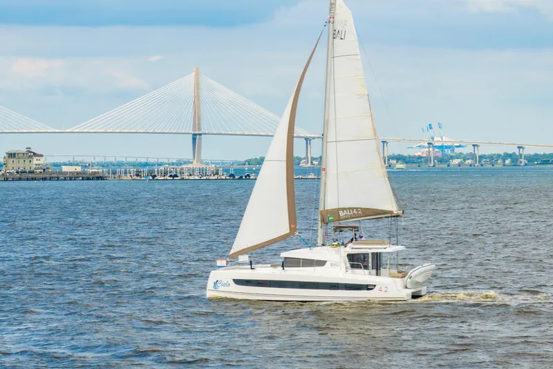Slide: The Image of Sailboat Bali 4.2 cruising near a bridge, 2023 model, on a sunny day. - 119