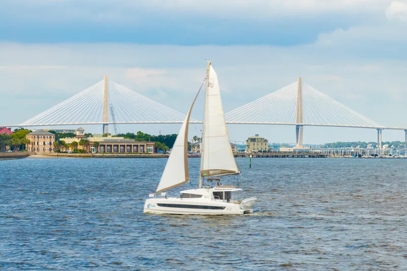 Slide: The Image of Sailboat Bali 4.2 cruising near a bridge, 2023 model, scenic waterfront view. - 120