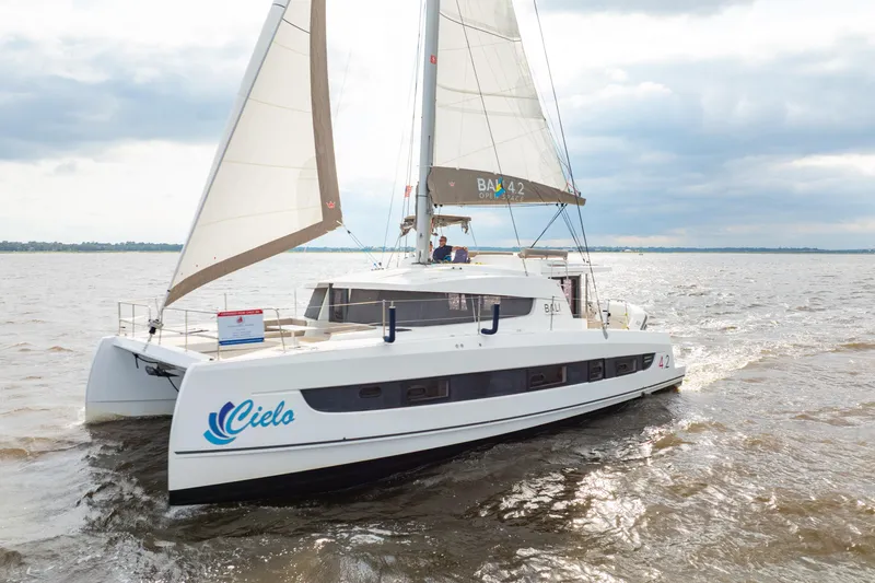 Slide: The Image of Sailing catamaran Bali 4.2, 2023 model, cruising on open water under cloudy skies. - 2