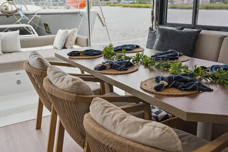 Slide: The Image of Elegant dining setup on a 2023 Bali 4.2 yacht, featuring woven chairs and nautical decor. - 58