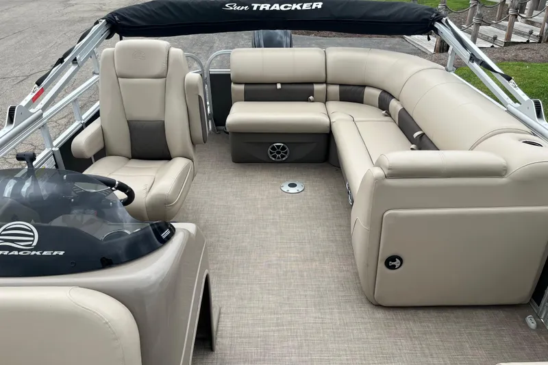 Slide: The Image of 2022 Sun Tracker Party Barge 20 DLX interior with beige seating and helm. - 9