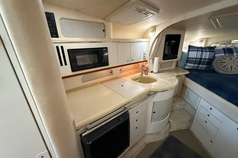 Slide: The Image of 2001 Sea Ray 310 Sundancer interior with kitchenette and cozy sleeping area. - 12