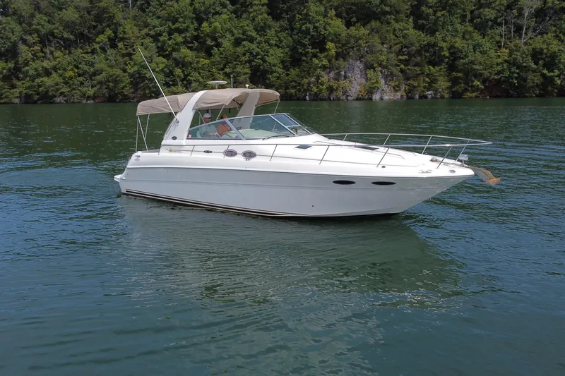 Slide: The Image of 2001 Sea Ray 310 Sundancer boat cruising on a serene lake with lush green backdrop. - 4