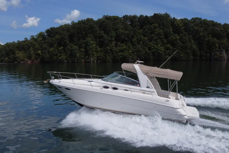 Slide: The Image of 2001 Sea Ray 310 Sundancer cruising on a serene lake with lush forest backdrop. - 6