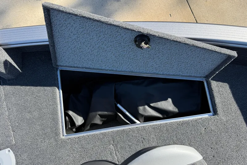 Slide: The Image of Open storage compartment in 2026 Lund 1875 Pro Guide boat, featuring carpeted interior. - 12