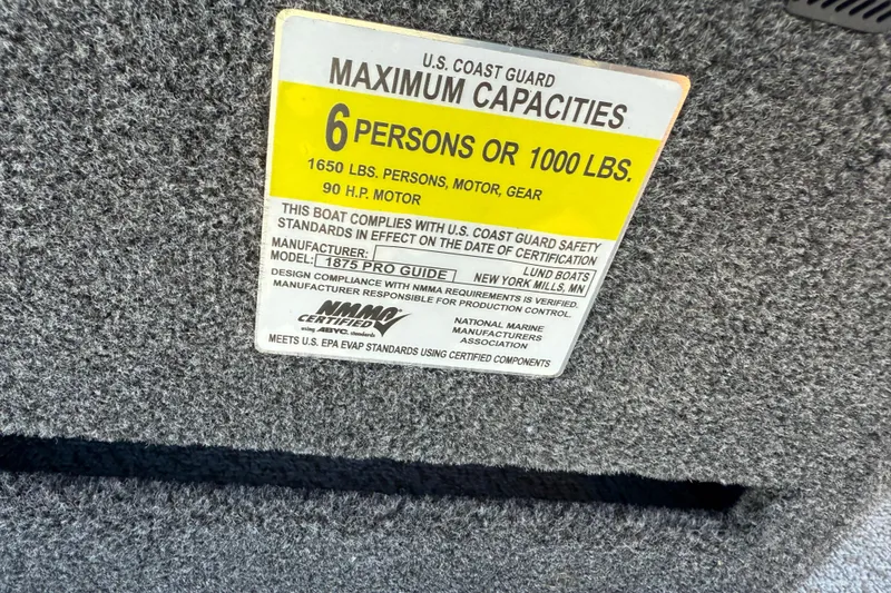Slide: The Image of U.S. Coast Guard capacity label on 2026 Lund 1875 Pro Guide boat, 6-person limit. - 17