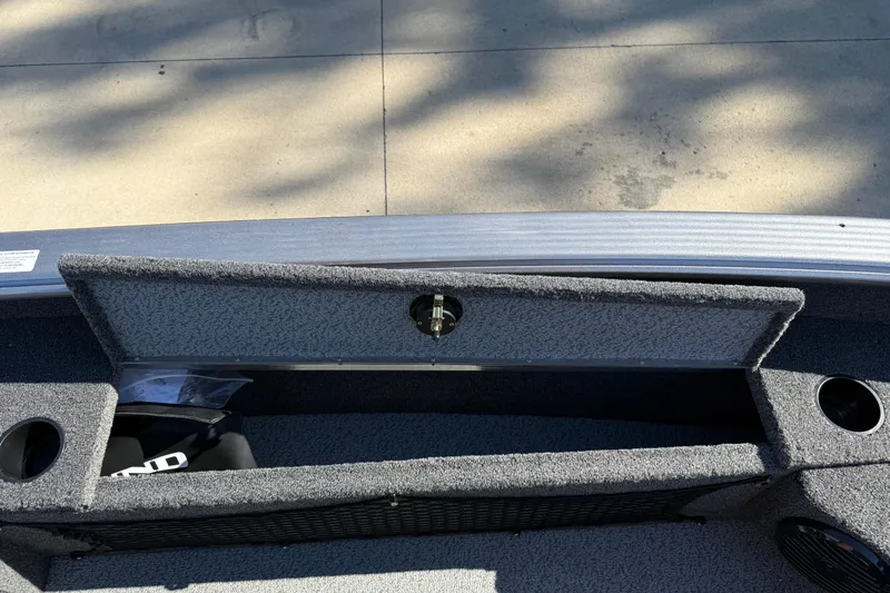 Slide: The Image of 2026 Lund 1875 Pro Guide boat storage compartment with open lid and cup holders. - 19