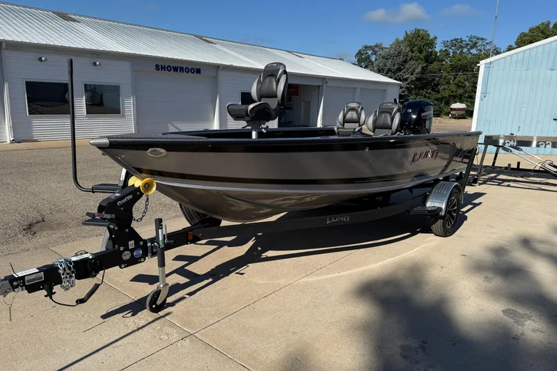 Slide: The Image of 2026 Lund 1875 Pro Guide boat on trailer outside showroom, sunny day. - 3