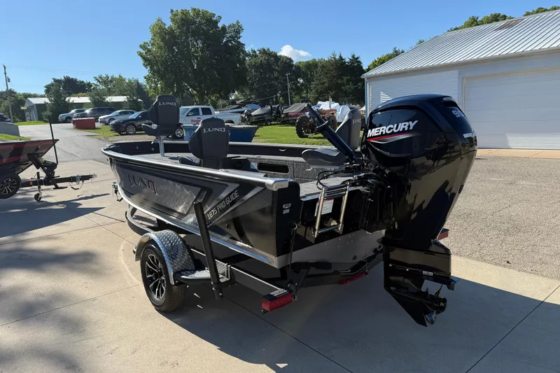 Slide: The Image of 2026 Lund 1875 Pro Guide boat with Mercury engine, parked outdoors on a sunny day. - 5