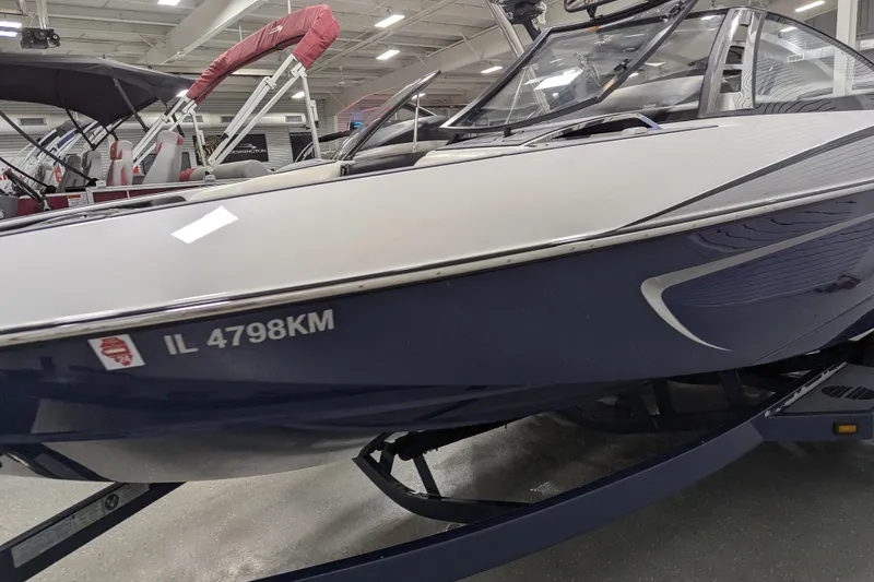 Slide: The Image of 2012 Malibu Wakesetter VLX boat displayed indoors, featuring sleek design and registration number IL 4798KM. - 12