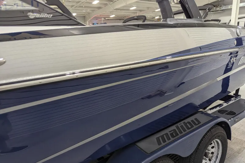 Slide: The Image of 2012 Malibu Wakesetter VLX boat, blue and white exterior, displayed indoors. - 14