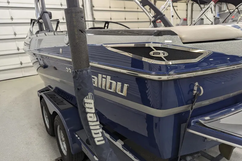 Slide: The Image of 2012 Malibu Wakesetter VLX boat in a garage, showcasing sleek blue design and branding. - 16