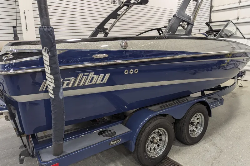 Slide: The Image of 2012 Malibu Wakesetter VLX boat in a showroom, blue with silver accents. - 19