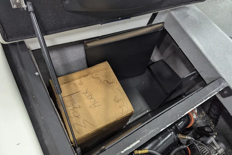 Slide: The Image of Open storage compartment in 2012 Malibu Wakesetter VLX boat with cardboard box inside. - 23